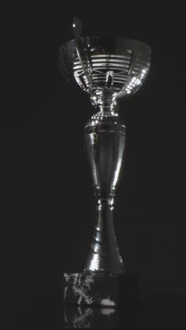 Vertical-Video-Studio-Still-Life-Shot-Of-Rotating-Sports-Trophy-Against-Black-Background-